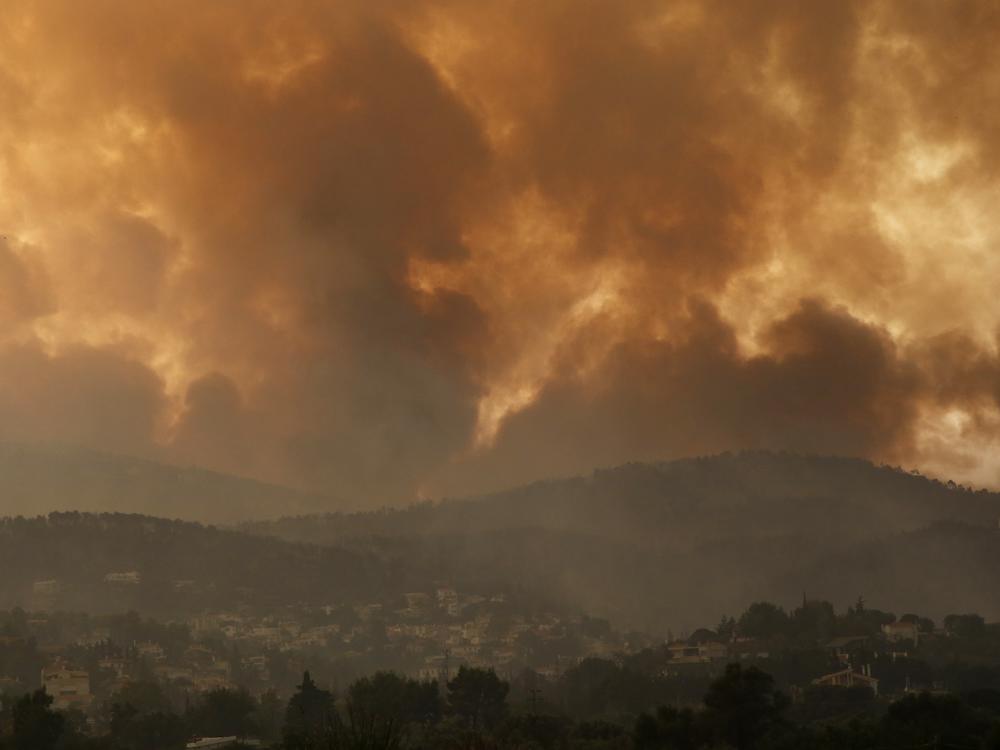 Smoke spreads over Parnitha mountain during a wildfire in Ippokratios Politia village, about 21 miles north of Athens, Greece on Friday. Thousands of people fled wildfires burning out of control in Greece and Turkey on Friday, including a major blaze just north of the Greek capital of Athens.