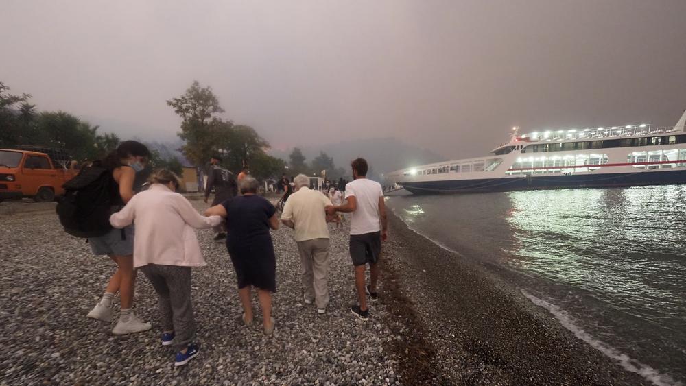 People embark a ferry during an evacuation from Kochyli beach as wildfire approaches near Limni village on the island of Evia on Friday.