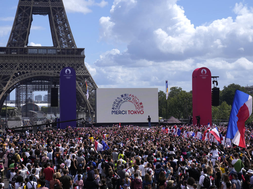 Spectators gather by the Eiffel Tower in Paris as part of the handover ceremony during the closing ceremony of the Tokyo Olympic games.