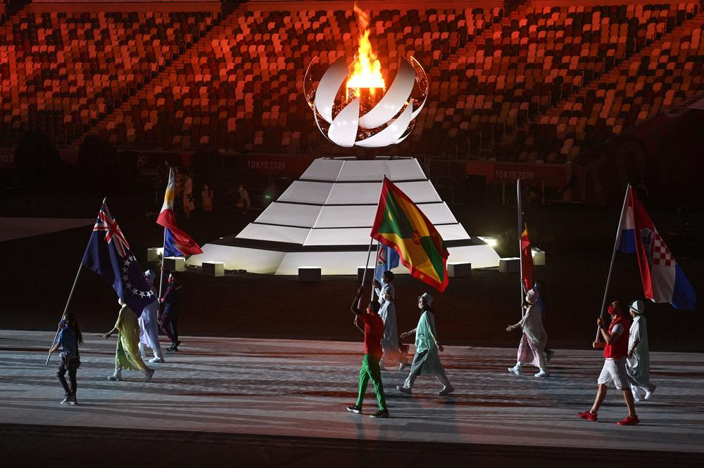 Athletes carrying nations' flags walk past the Olympic flame as they enter the stadium during the closing ceremony of the Tokyo 2020 Olympic Games.