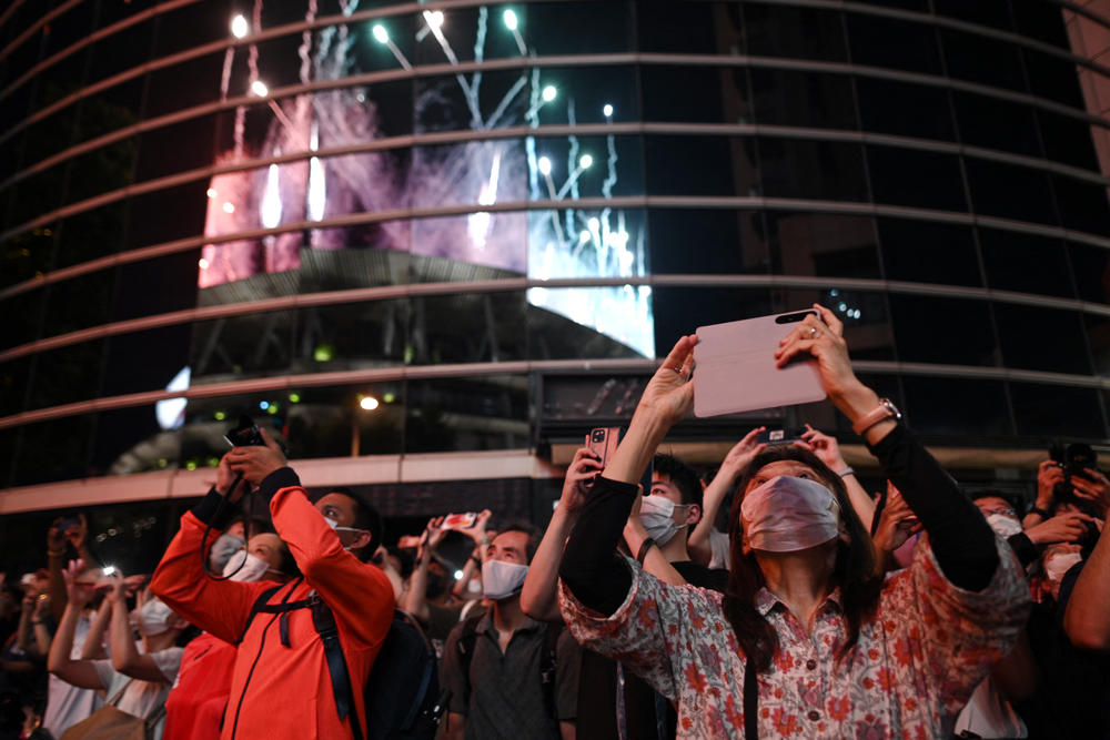 Bystanders take images of fireworks lighting up the sky over the Olympic Stadium.