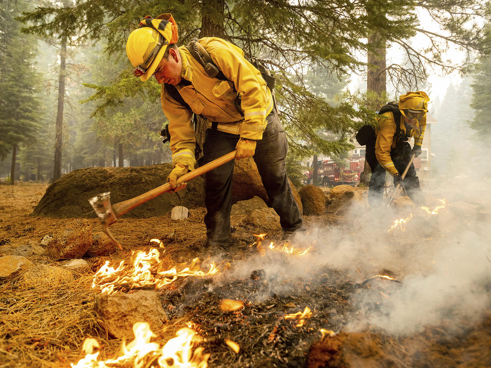 Firefighters Erik Padilla (left) and Joe Young extinguish hot spots last week while protecting Lake Almanor West homes from the Dixie Fire in California's Plumas County.