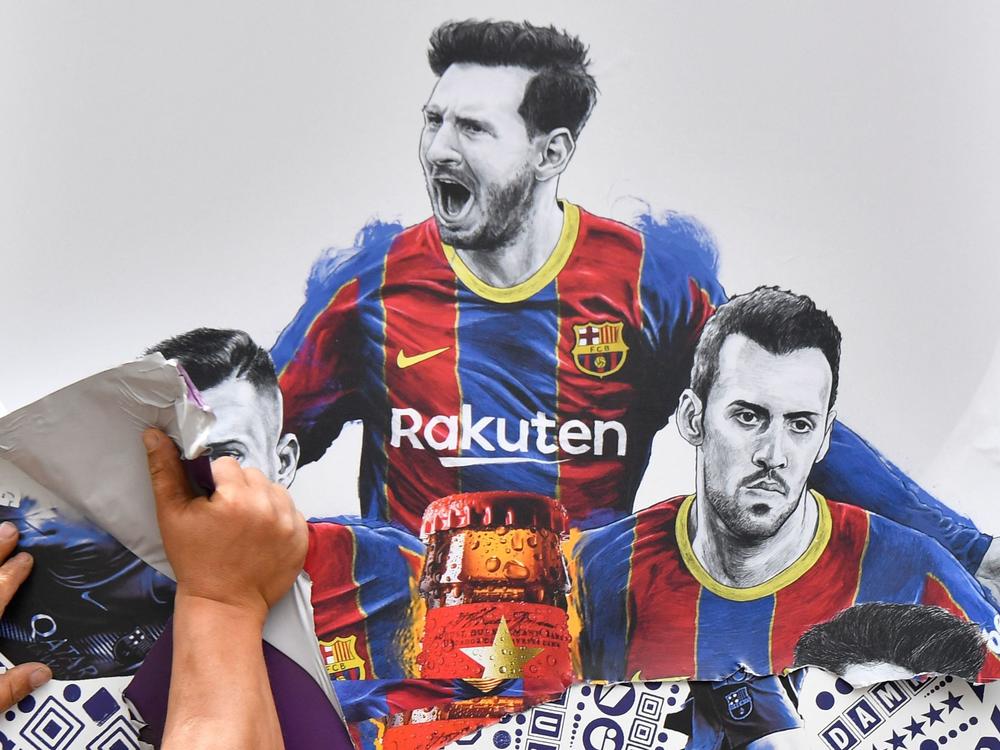 A worker removes posters featuring FC Barcelona's departing Argentinian star Lionel Messi on Tuesday. Messi is poised to join Paris Saint-Germain.