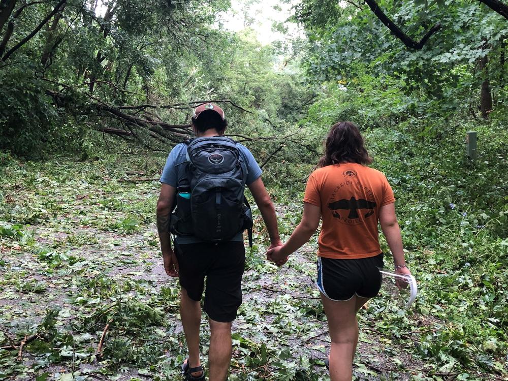 Nick Bergus and his wife Laura Bergus walk hand in hand over tree debris left behind by the derecho near Cedar Rapids, Iowa, on Aug. 10, 2020.