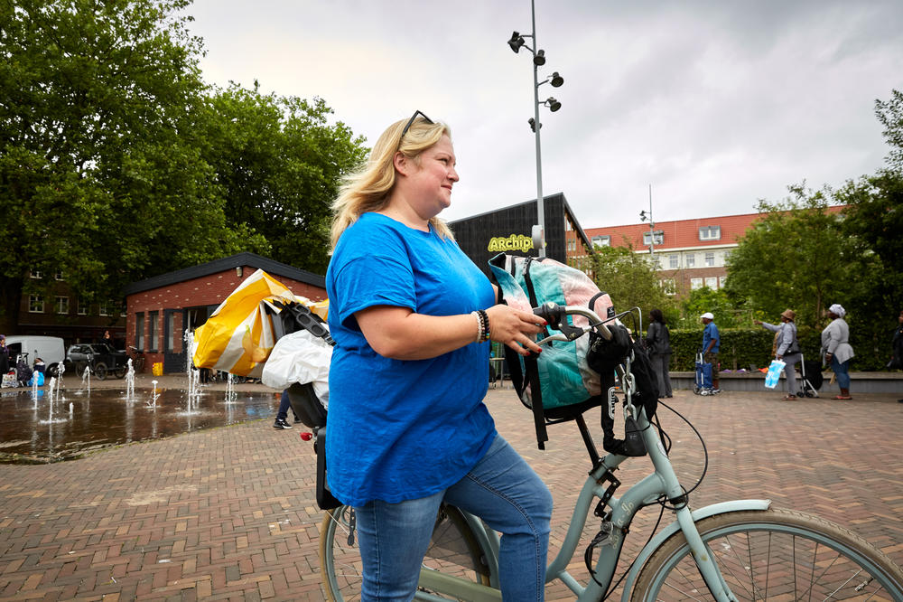 Anna Ottens, 41, walks her bike near the Archipelago Community Center in Amsterdam. The single mom of three relies on the center's food bank to supplement the groceries she buys with government aid.