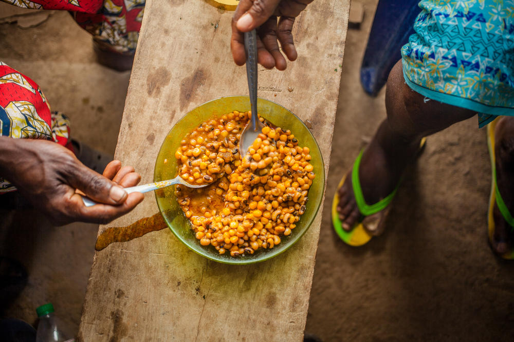 Femi Oyekan Moses, left, and his wife Mary share a dish of boiled beans and corn at their home in Oyo, Nigeria. Before the pandemic, he says, 