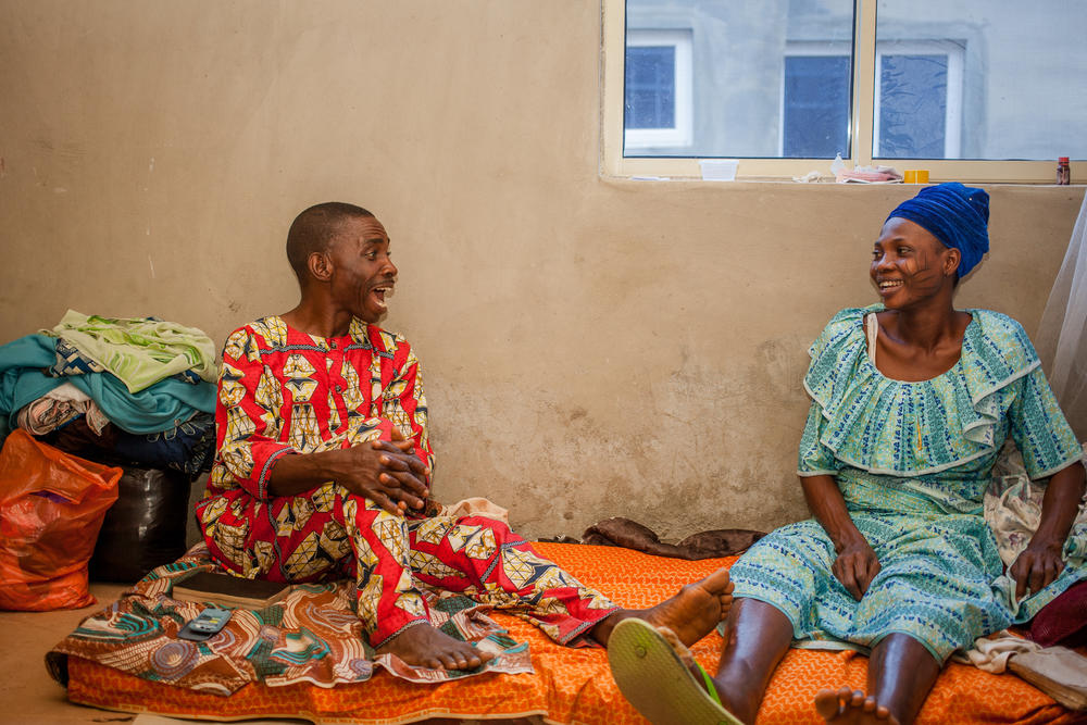 Femi and Mary sit together at home. Femi says he remains optimistic the family will return to the life they had before the pandemic. For now, he says, the support of friends, family and church helps them cope.