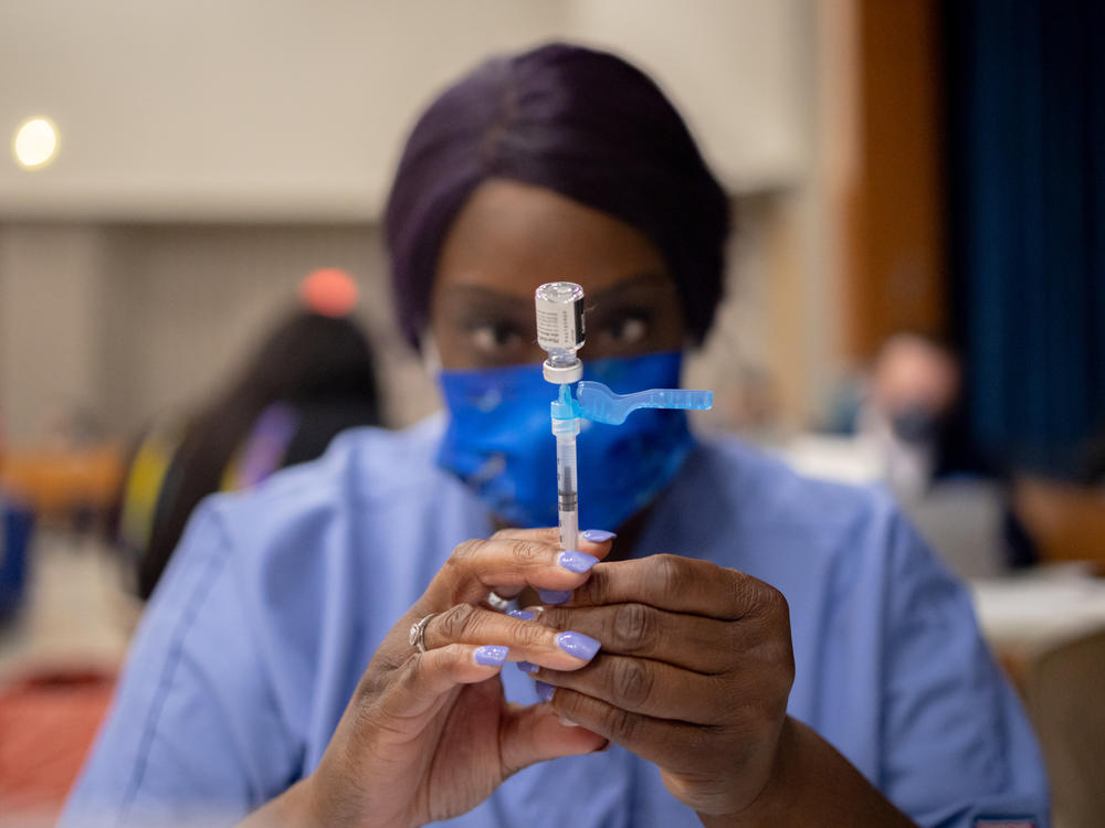 A health care worker prepares a dose of the Pfizer-BioNTech COVID-19 vaccine last week at West Philadelphia High School in Philadelphia. Dr. Anthony Fauci says he backs mandatory vaccines for teachers, citing a 