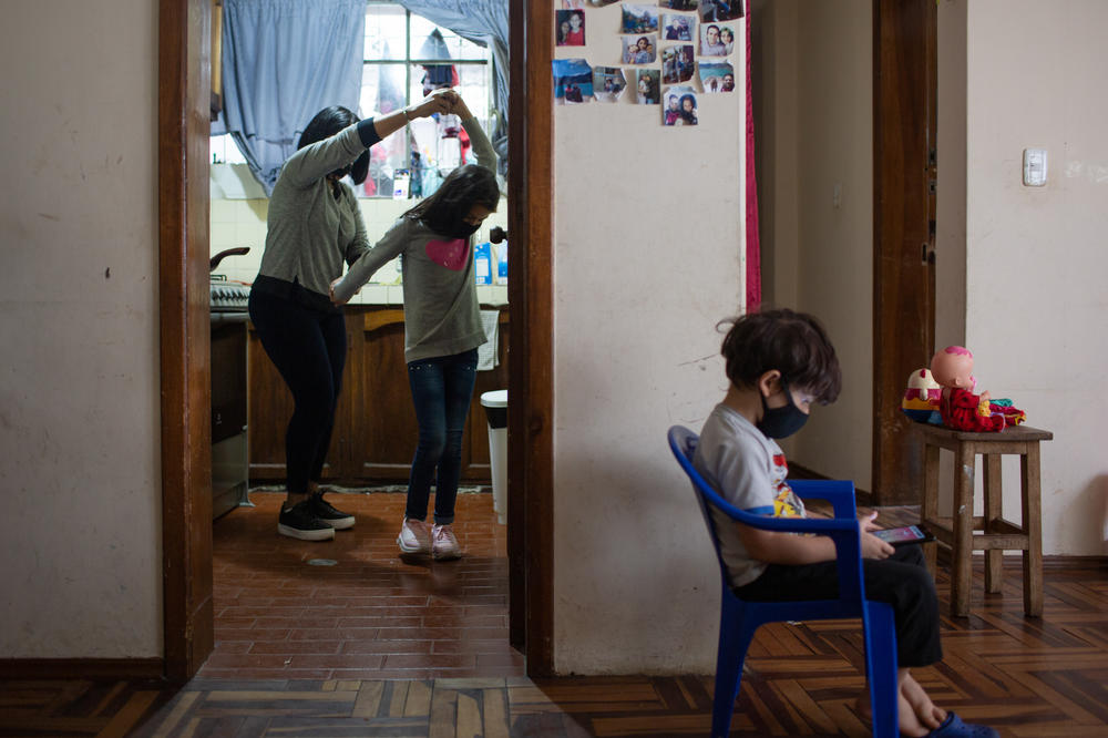 Barreto, left, dances with her granddaughter in the kitchen. She lives with her son, daughter-in-law and their two kids. Even though the family is having a tough time, Barreto says she tries to look for ways to be happy. 