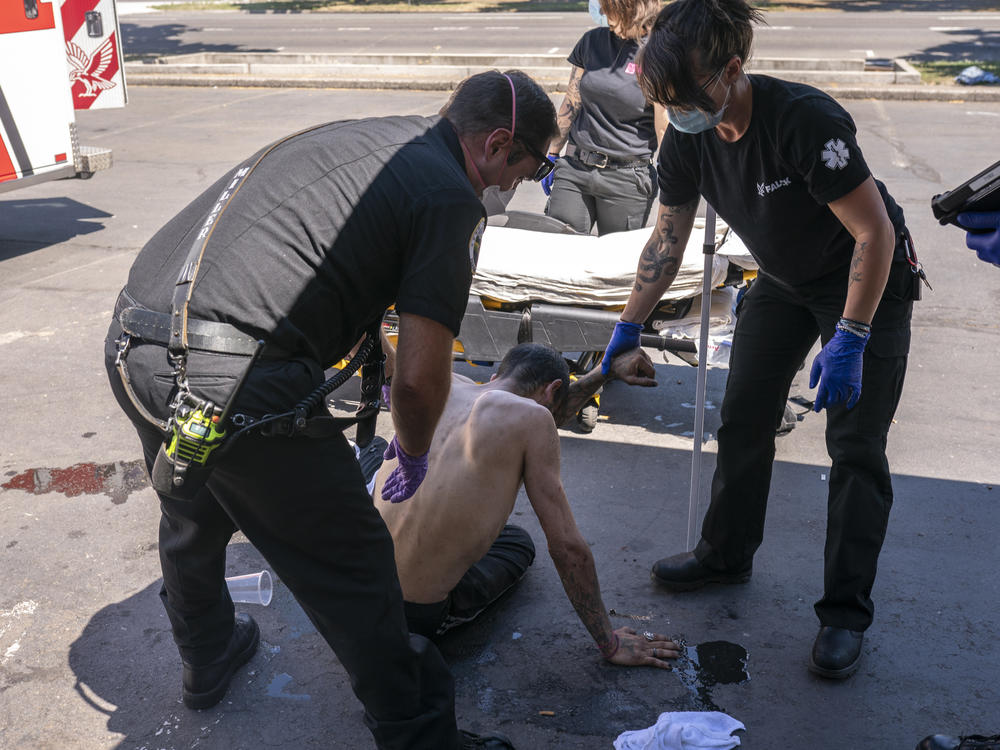 Salem, Ore., Fire Department Capt. Matt Brozovich (left) and Falck Northwest ambulance personnel help treat a man experiencing heat exposure at a cooling center during a heat wave in the Pacific Northwest in June.