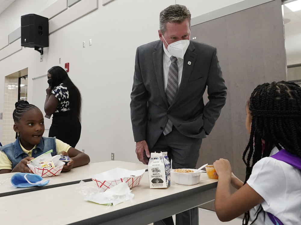 Mike Burke, Palm Beach County superintendent of schools, chats with students as they eat breakfast on Tuesday. The school district has asked 440 students to quarantine just days into the school year.