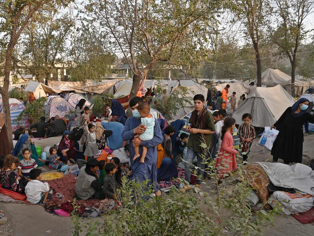 Internally displaced Afghan families, who fled from Kunduz, Takhar and Baghlan provinces due to battles between the Taliban and Afghan security forces, sit in front of temporary tents on Wednesday at Sara-e-Shamali in Kabul.