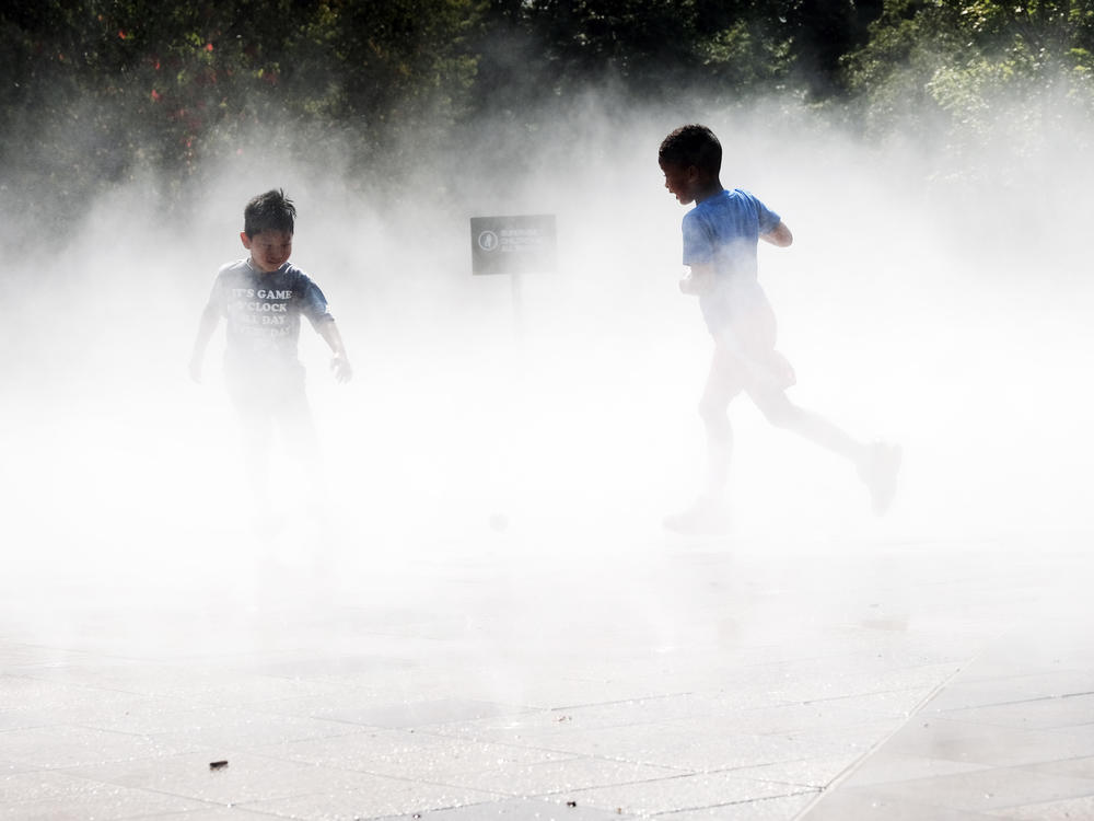 Children beat the heat Thursday in a misting pool at a park in Queens as temperatures reach into the 90s in New York City.