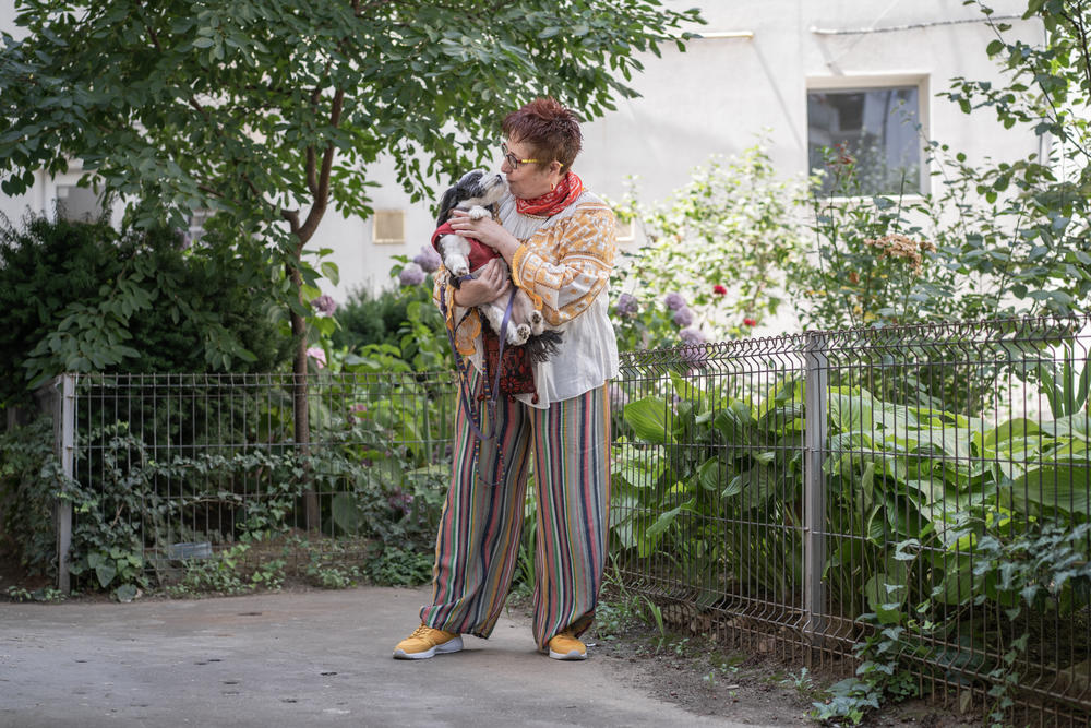 Daniela Draghici holding her dog, Mini, while on a walk in the backyard of her apartment building in Bucharest.