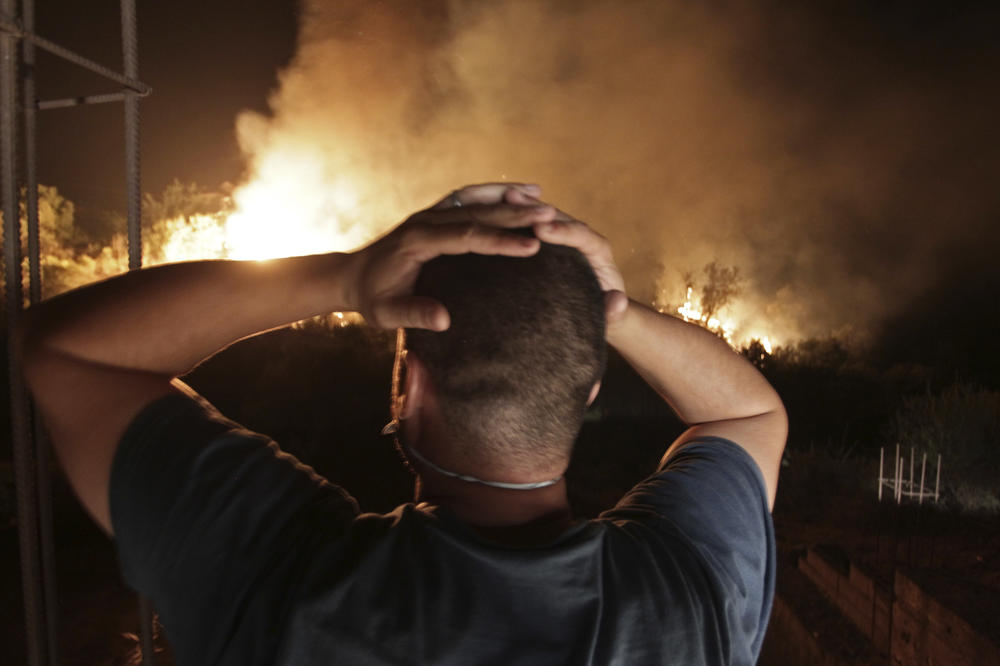 A man looks at a forest fire near the village of Larbaa Nath Irathen, neat Tizi Ouzou, in the mountainous Kabyle region, 60 miles east of Algeria's capital of Algiers. Wildfires in Algeria that already have killed at least 69 people burned through the mountainous Berber region as the North African country contended Thursday with a heat wave like the ones fueling fires in Southern Europe.