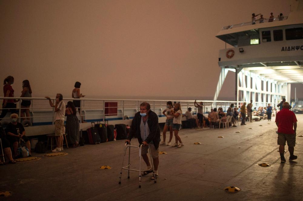 A man walks with a rollator onboard a ferry at the port of the village of Pefki, during a wildfire at Pefki village on Evia (Euboea) island, the second largest Greek island, on Aug. 8. Firefighters tried on Aug. 9, to prevent fires from reaching key communities and a thick forest that could fuel an inferno that one official said has destroyed hundreds of homes in seven days.