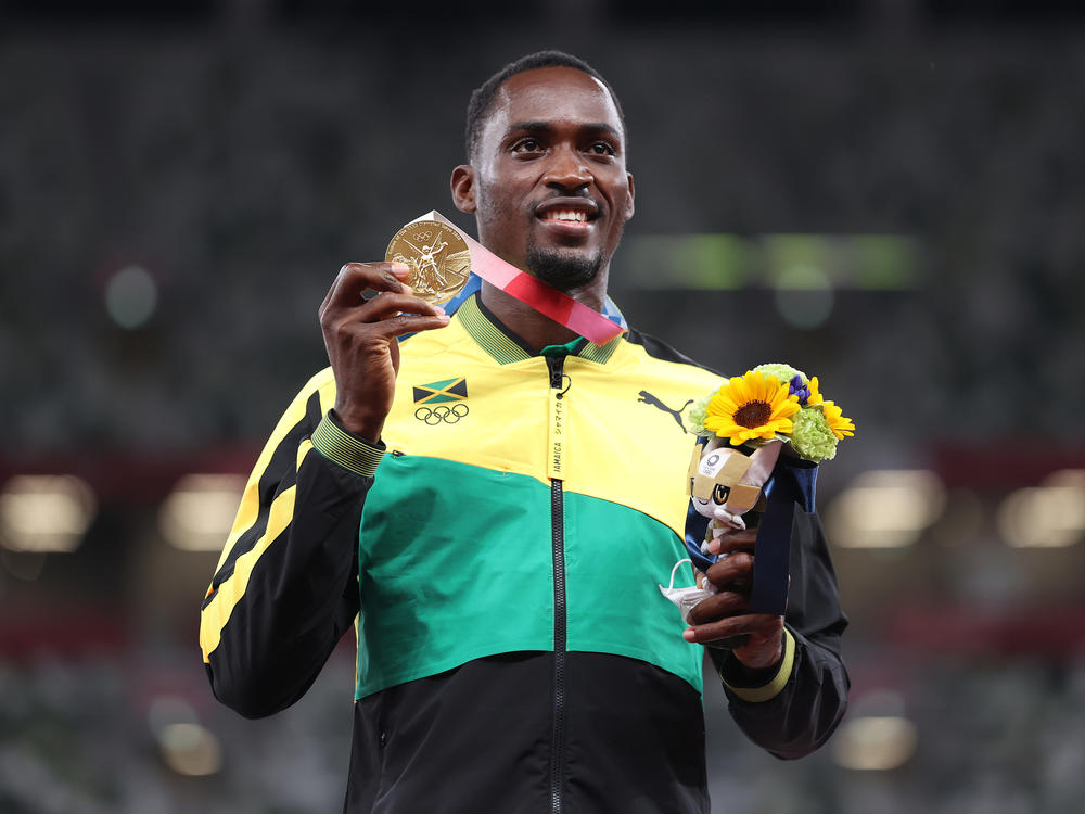Gold medalist Hansle Parchment of Jamaica holds up his medal on the podium during the medal ceremony for the men's 110-meter hurdles on Aug. 5.