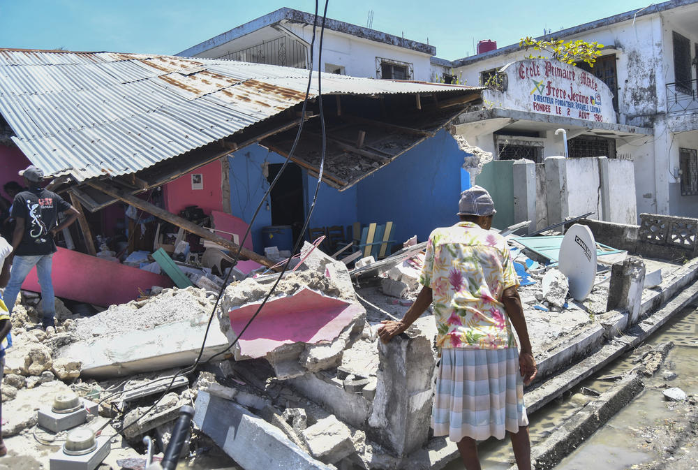 <strong>Sat., Aug. 14:</strong> A woman stands in front of a destroyed home in the aftermath of an earthquake in Les Cayes, Haiti.