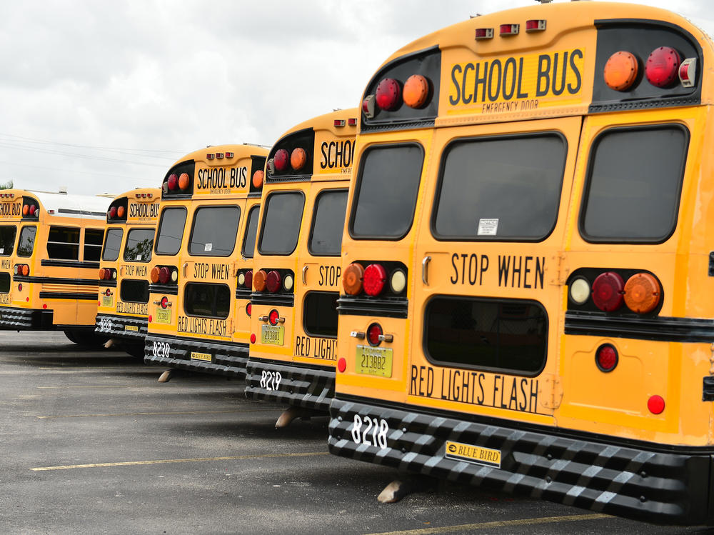 A fleet of Broward County School Buses are parked in a lot on July 21, 2020, in Pembroke Pines, Fla. Three county educators have died of complications from the coronavirus.