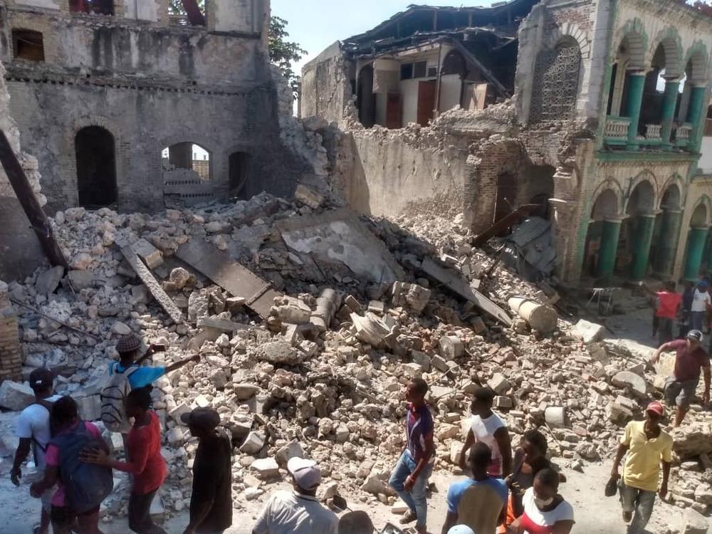 <strong>Sat., Aug. 14:</strong> People inspect damaged buildings.