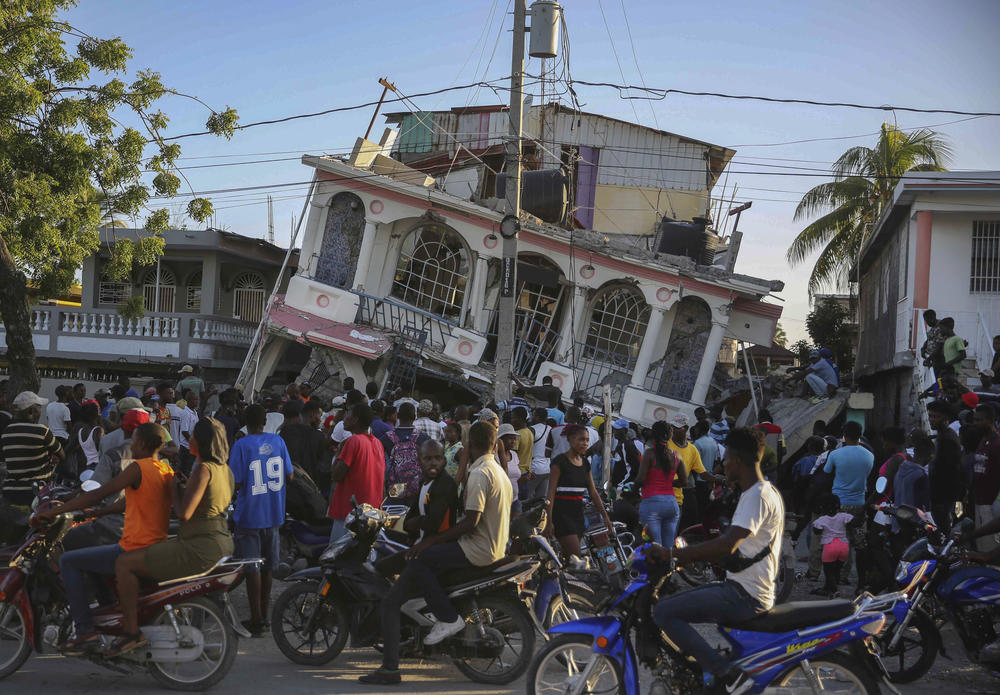 <strong>Sat., Aug. 14:</strong> People gather outside the Petit Pas Hotel, destroyed by the earthquake in Les Cayes, Haiti.