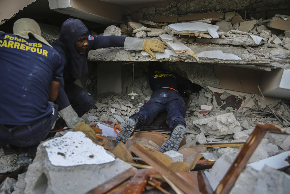 <strong>Sun. Aug. 15:</strong> Firefighters search for survivors inside a collapsed building in Les Cayes, Haiti.