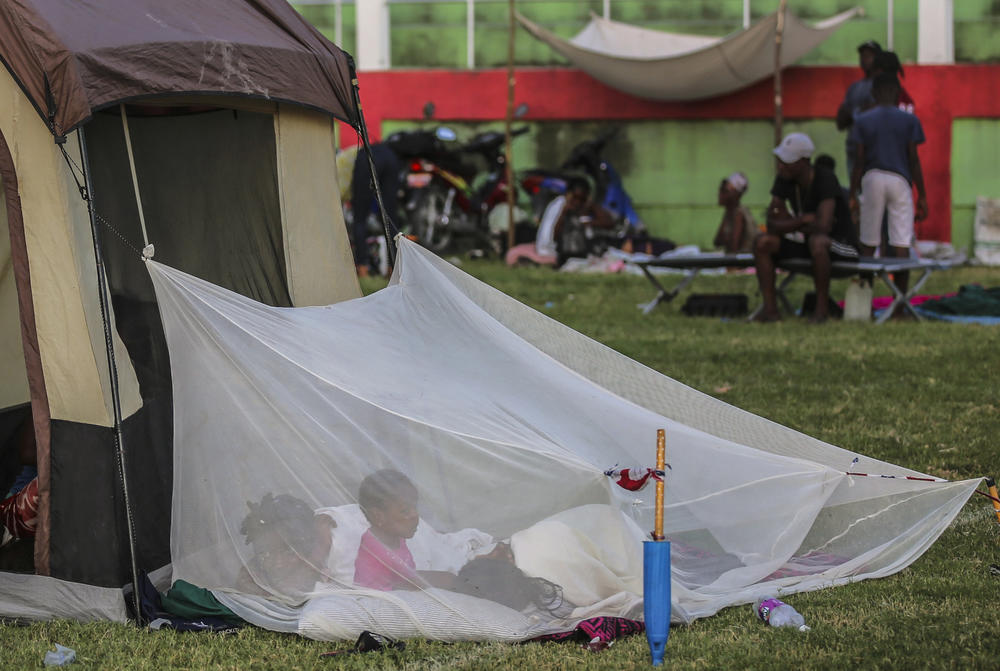 <strong>Sun., Aug. 15:</strong> A family wakes up inside a mosquito net tent after spending the night at a soccer field in Les Cayes, Haiti.
