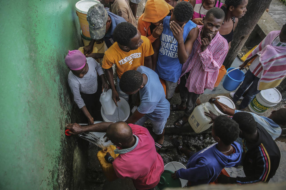 <strong>Sun., Aug. 15:</strong> People displaced by the earthquake collect water after sleeping in the streets in Les Cayes, Haiti.