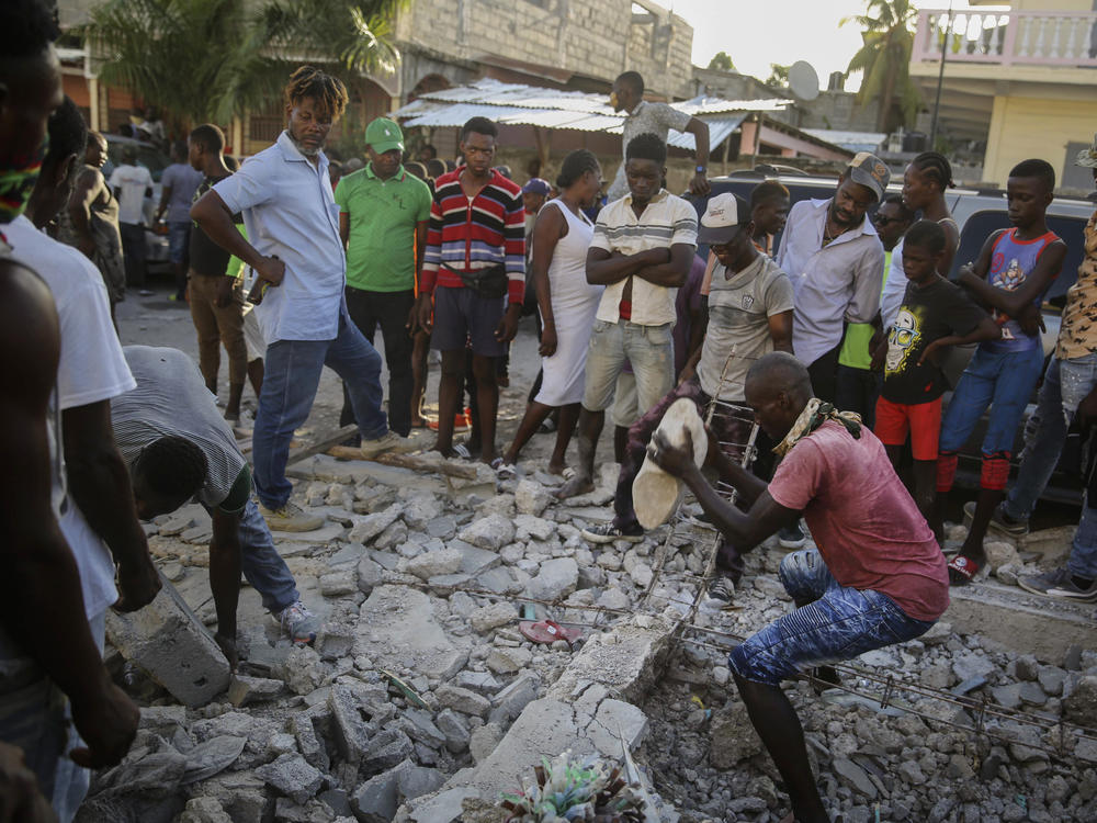 A man digs with a stone through the rubble of a house destroyed by the earthquake in Les Cayes, Haiti, on Sunday.