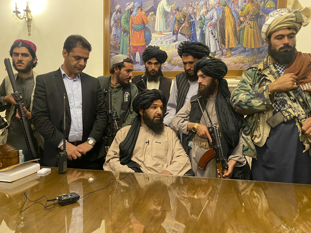 Taliban fighters take control of Afghan presidential palace in Kabul on Sunday, after President Ashraf Ghani fled the country. The person second from left is a former bodyguard for Ghani.