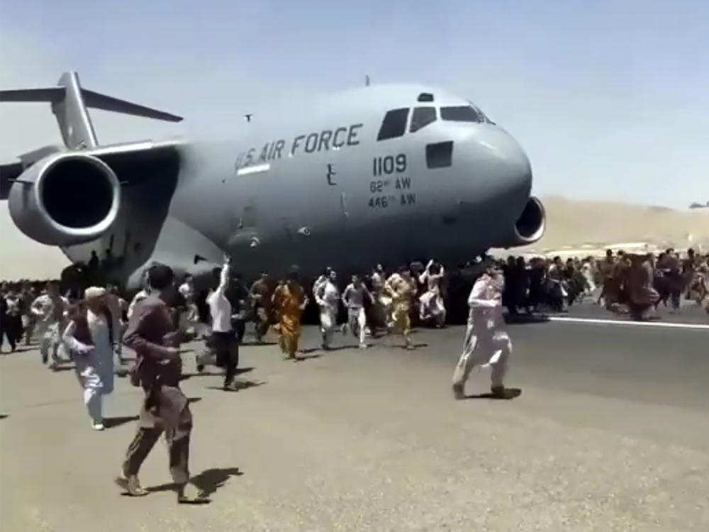 People run alongside a U.S. Air Force C-17 transport plane as it moves down a runway of the Kabul airport on Monday.
