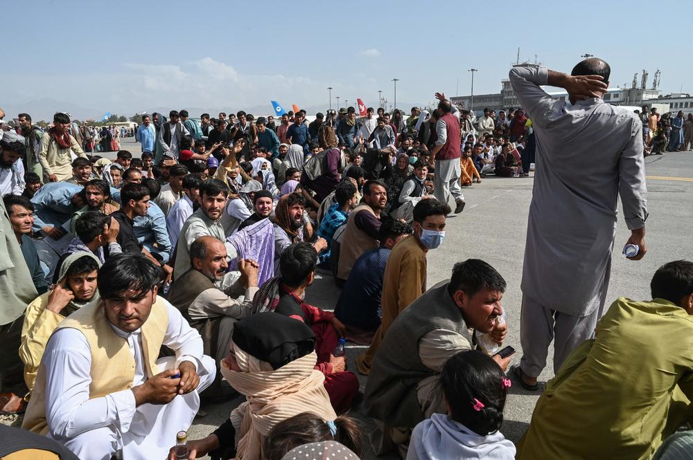 Afghan passengers sit as they wait to leave the Kabul airport on Monday, as thousands of people mobbed the airport trying to flee the Taliban's hardline brand of Islamist rule.