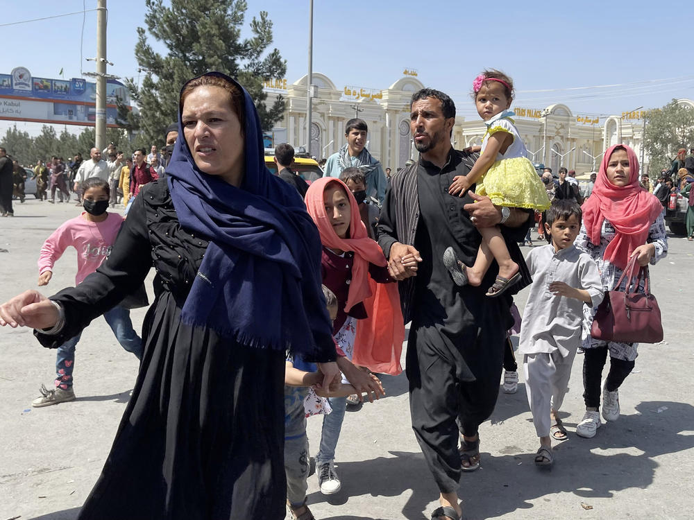 An Afghan family rushes to the airport as they flee.