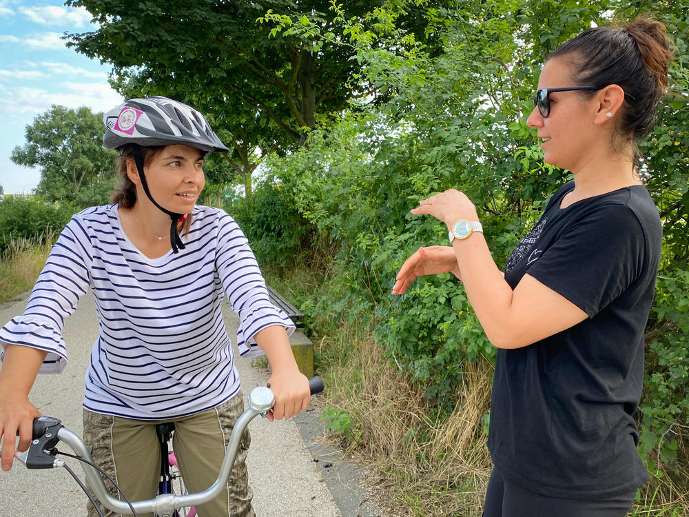 A volunteer, right, speaks with one of the women learning to ride a bicycle.
