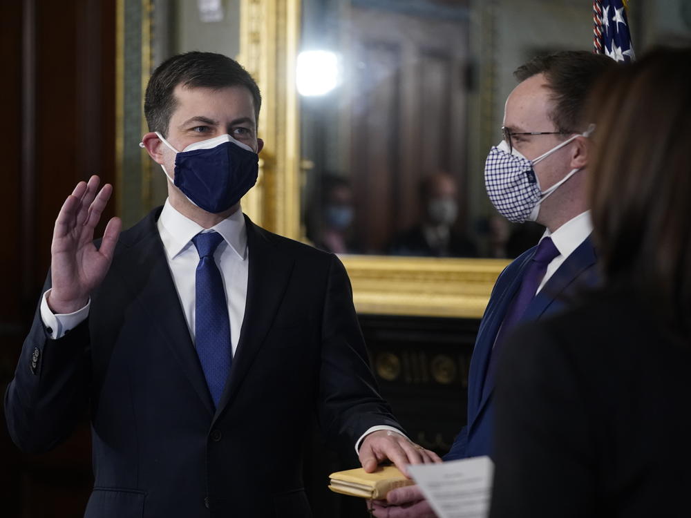 Pete Buttigieg, with his hand on the Bible held by husband Chasten Buttigieg, gets sworn in as transportation secretary by Vice President Harris on Feb. 3.