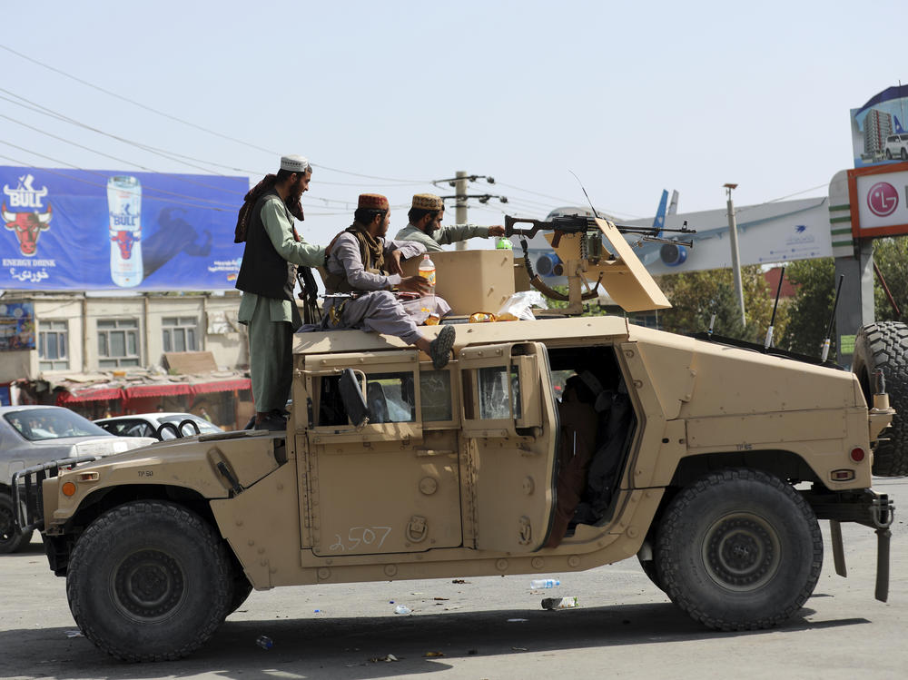 Taliban fighters stand guard in front of airport, in Kabul, Afghanistan, on Monday. Thousands of people rushed the tarmac and pushing onto planes in desperate attempts to flee the country as the Taliban advanced.