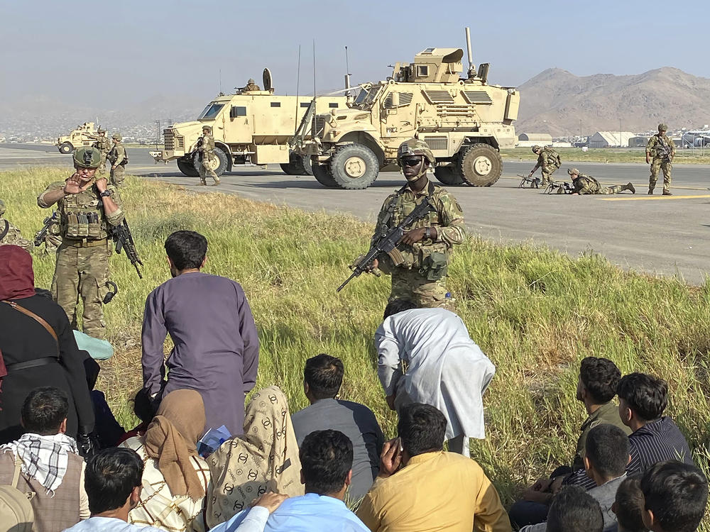 U.S soldiers stand guard along a perimeter at the international airport in Kabul, Afghanistan, Monday. After the sudden Taliban takeover over the weekend, trapped Afghans  rushed the tarmac and clung to U.S. military planes deployed to fly out staffers of the U.S. Embassy, which shut down Sunday, and others.