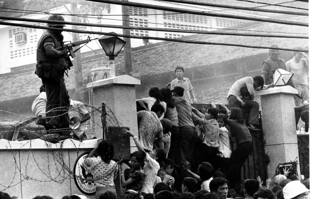 Vietnamese people scale the wall of the U.S. Embassy in Saigon, trying to get to the helicopter pickup zone, just before the end of the Vietnam War on April 29, 1975.