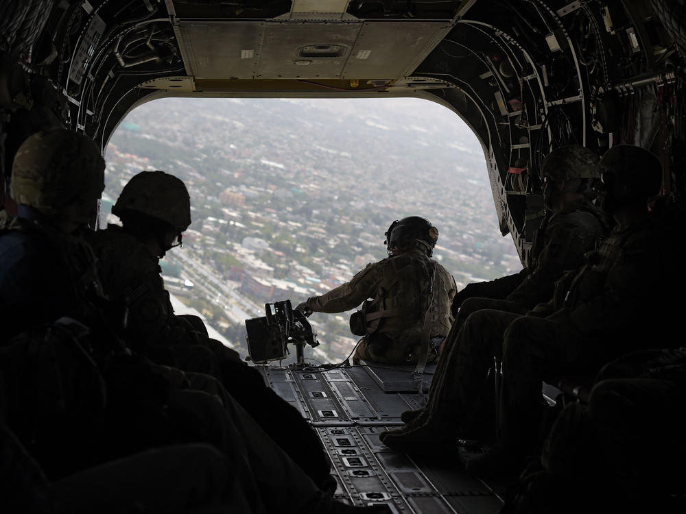 A U.S. soldier sits in the rear of a Chinook helicopter while flying over Afghanistan's capital of Kabul in August 2017.