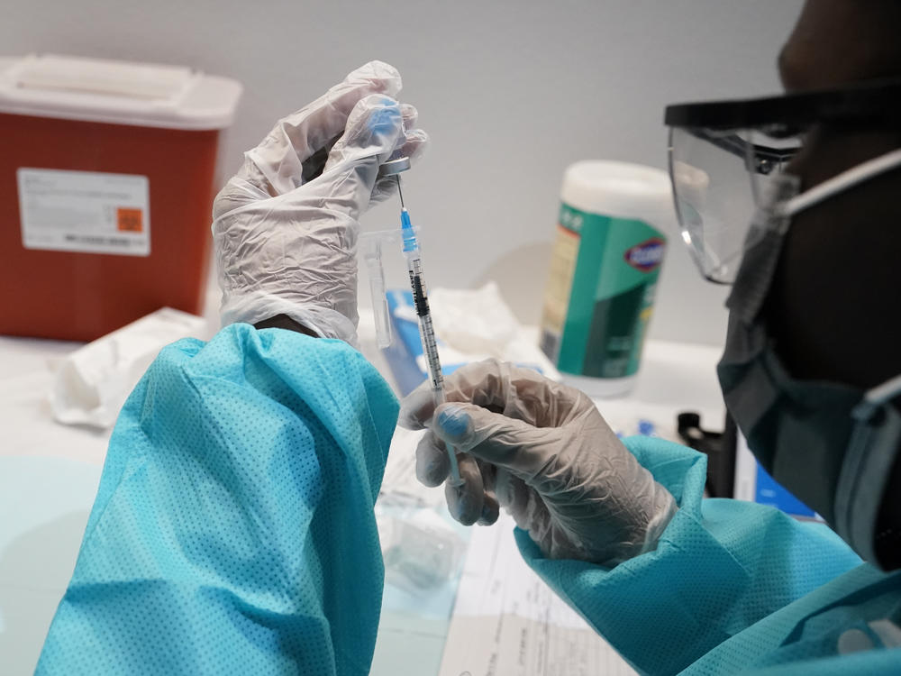 A health care worker fills a syringe with the Pfizer COVID-19 vaccine in July in New York. U.S. officials are recommending that Americans get COVID-19 booster shots to shore up their protection amid the surging delta variant and evidence the vaccines' effectiveness is falling.
