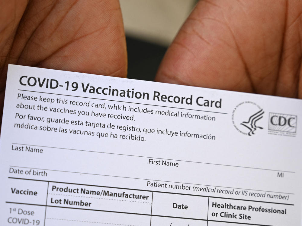 A health care worker displays a COVID-19 vaccination record card at a health center in Los Angeles earlier this month.