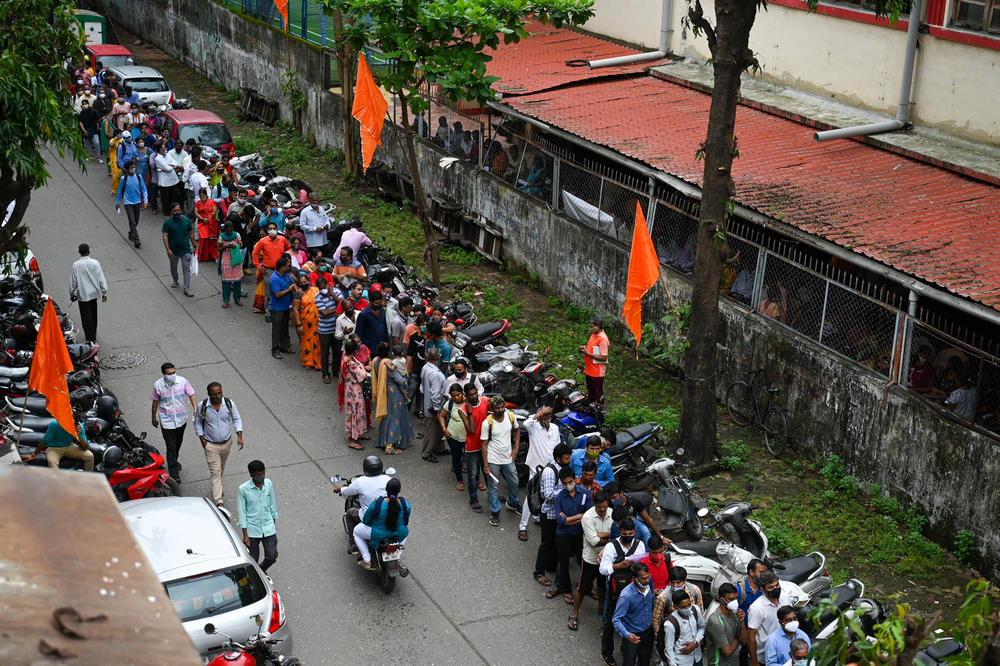 People wait Tuesday for a COVID-19 vaccine dose at a temporary vaccination center inside a school in Mumbai, India.