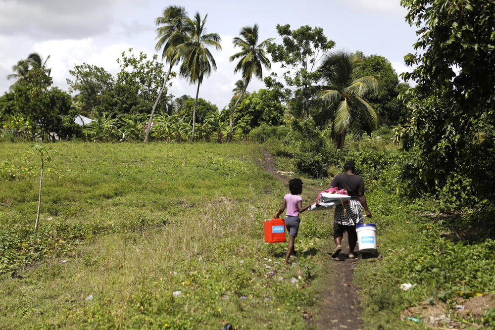 A family walks home after receiving relief supplies from UNICEF and the Haitian Red Cross.