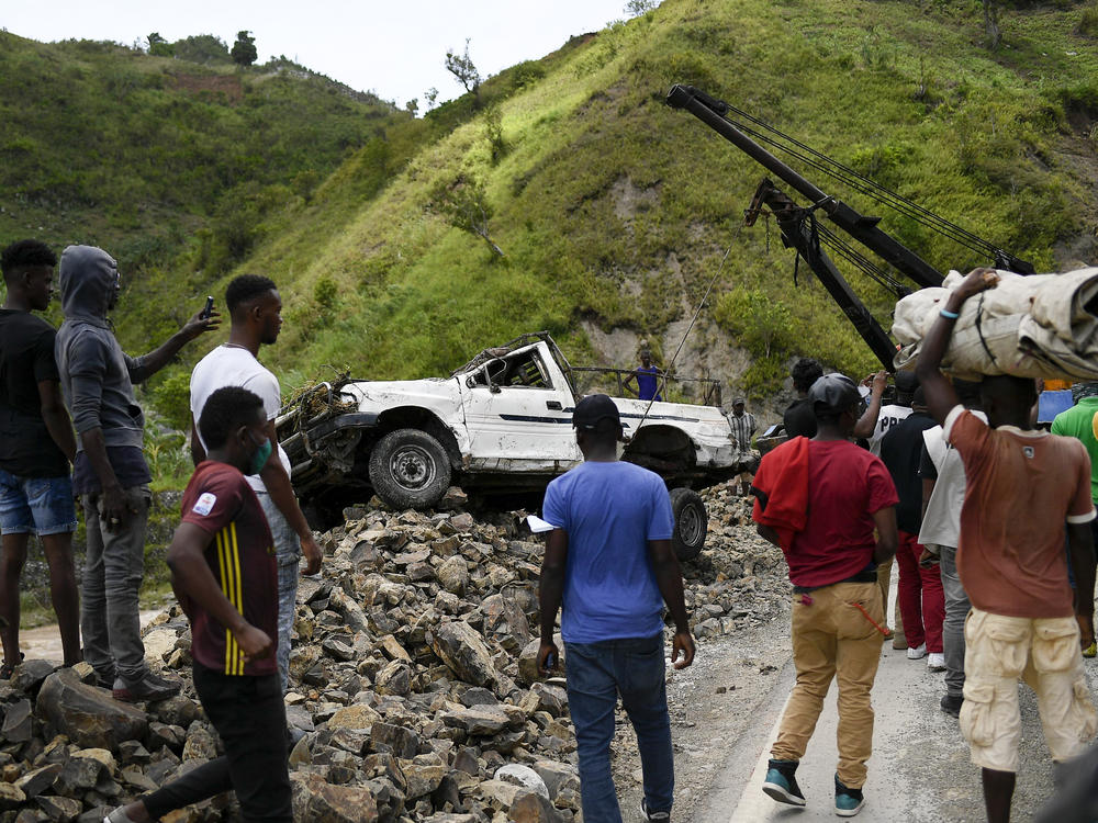 A crane removes a truck from a pile of rocks after landslides triggered by a 7.2-magnitude earthquake that hit four days prior in River Glass, Haiti, Wednesday, Aug. 18, 2021.