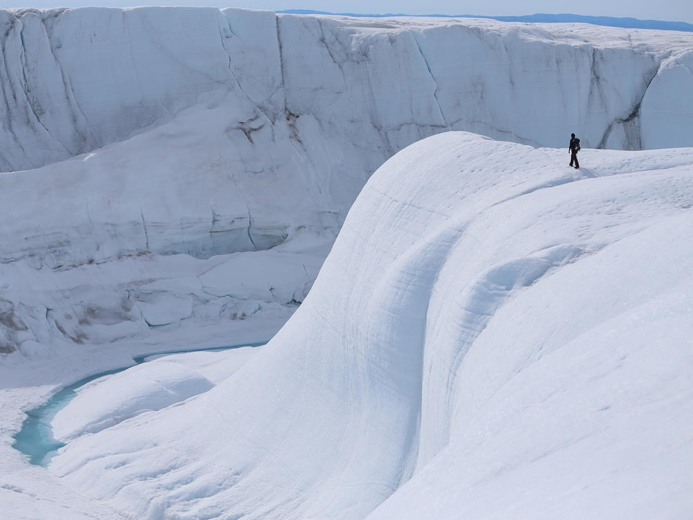 A researcher looks at a canyon created by a meltwater stream on the glacial ice sheet in Greenland in 2013.