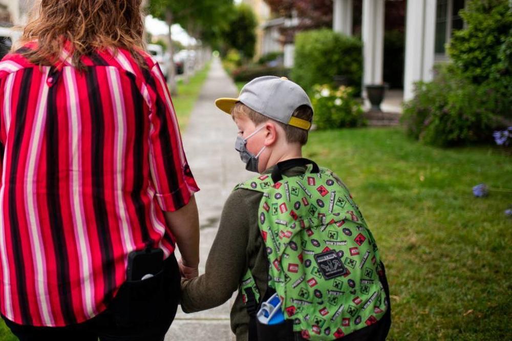 Stephanie Chenard held hands with her son, Desmond, 8, as they walked to his school in the San Francisco Bay Area last week. Later that evening, the school district reported four COVID-19 cases in four different schools.