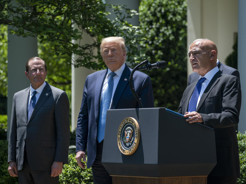 Then-Health and Human Services Secretary Alex Azar (left) and President Donald Trump listen as Moncef Slaoui of Operation Warp Speed speaks about the crash program to develop a COVID-19 vaccine in the White House Rose Garden in May 2020.