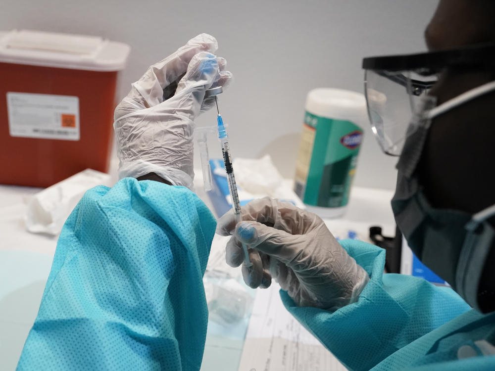 A health care worker fills a syringe with the Pfizer-BioNTech COVID-19 vaccine at the American Museum of Natural History in New York.