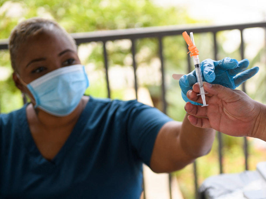 A nurse is handed a dose of the Pfizer COVID-19 vaccine before administering it to a college student during a mobile vaccination clinic at California State University, Long Beach on Aug. 11.