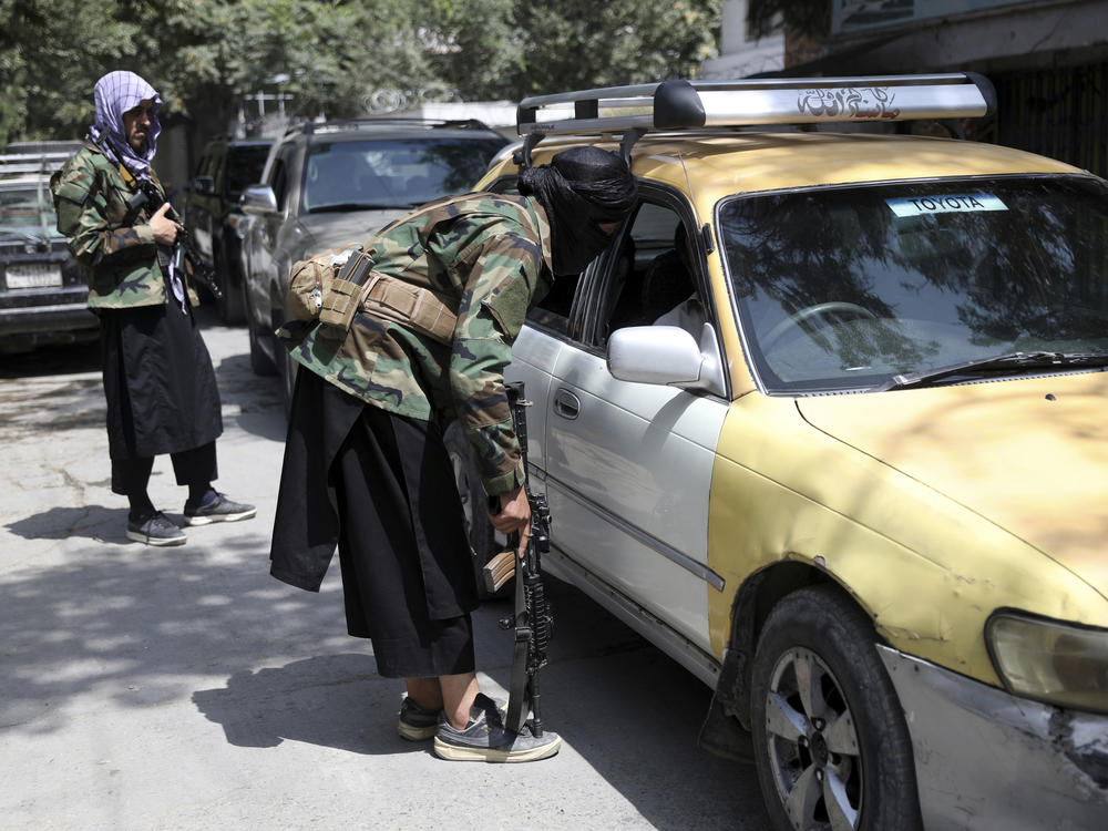 Taliban fighters search a vehicle at a checkpoint on the road in the Wazir Akbar Khan neighborhood in the city of Kabul, Afghanistan in August.
